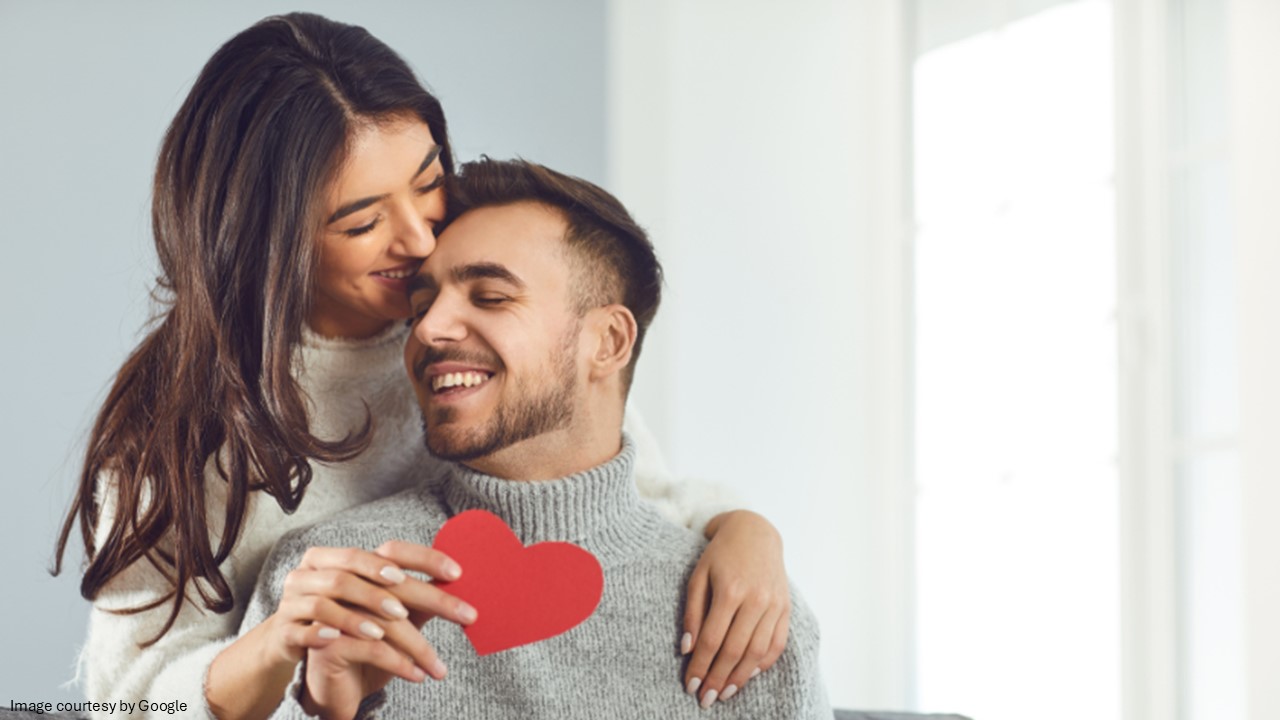 A couple holding a paper red heart