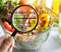 Magnifying glass showing nutrition facts on a healthy salad bowl