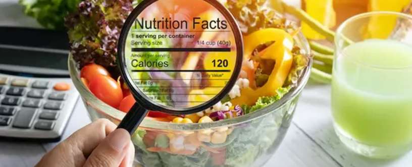 Magnifying glass showing nutrition facts on a healthy salad bowl