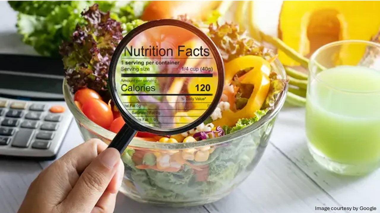 Magnifying glass showing nutrition facts on a healthy salad bowl