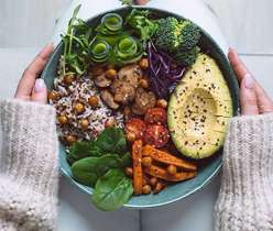 Hand holding a plate full of vegetarian food