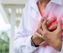 Man clutching chest experiencing early symptoms of a heart attack, highlighting the importance of recognizing warning signs and seeking medical help promptly.