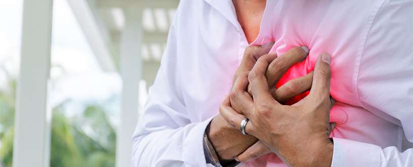 Man clutching chest experiencing early symptoms of a heart attack, highlighting the importance of recognizing warning signs and seeking medical help promptly.