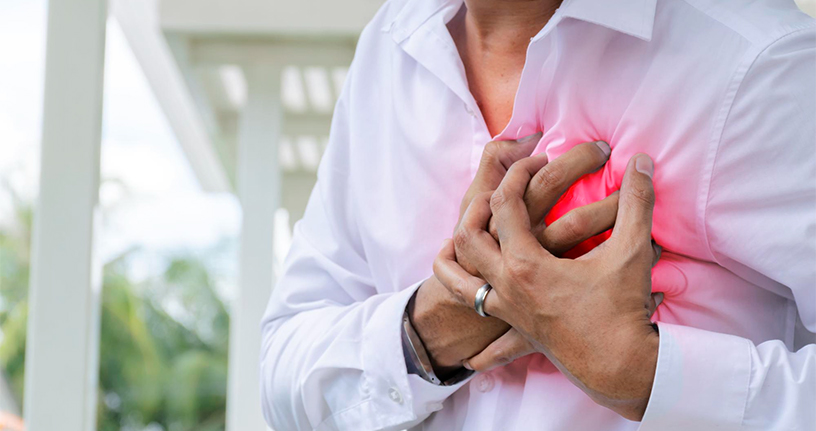 Man clutching chest experiencing early symptoms of a heart attack, highlighting the importance of recognizing warning signs and seeking medical help promptly.