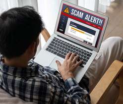 Man viewing a laptop alert about a scam pharmacy website — warning about counterfeit medication risks