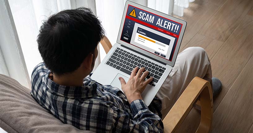 Man viewing a laptop alert about a scam pharmacy website — warning about counterfeit medication risks