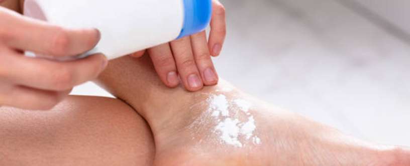 A hand applying antifungal power on leg