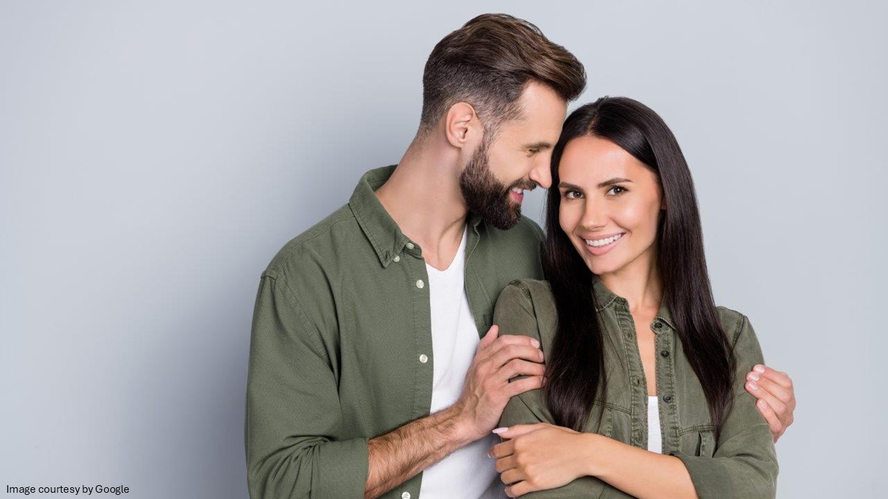 A man holding a lady by shoulder and smiling